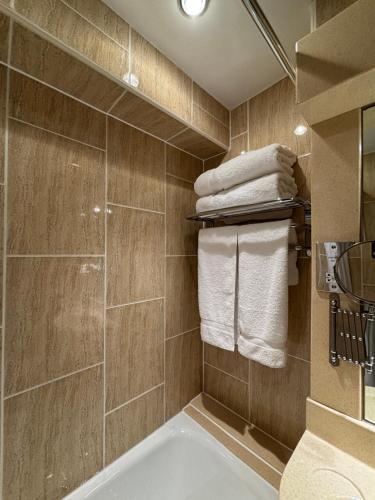 a bathroom with a tub and a shower with towels at The Liner at Liverpool in Liverpool