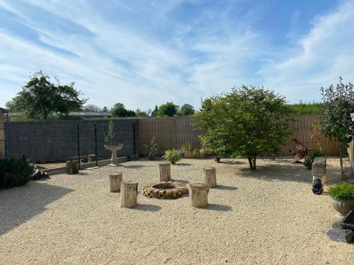 ein Hinterhof mit einer Feuerstelle, Bäumen und einem Zaun in der Unterkunft Petite maison de campagne in Sainte-Croix-sur-Mer