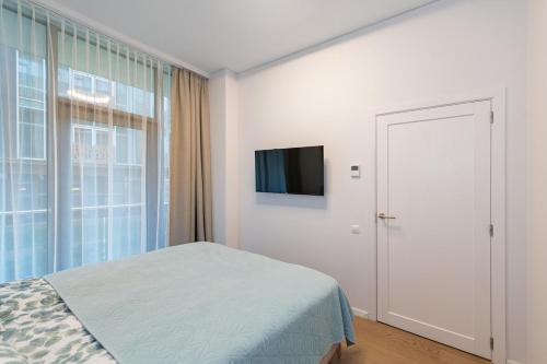 a bedroom with a bed and a tv and a window at Sun Sonata Apartments 1 in Druskininkai