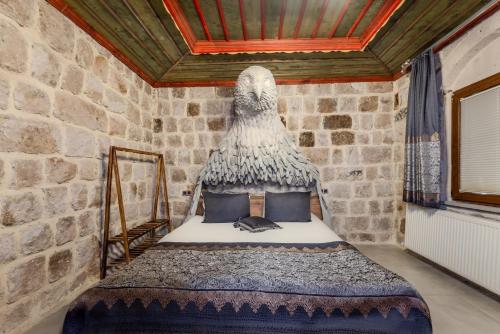 a bed in a room with a stone wall at Kayatas Cave Suites in Goreme