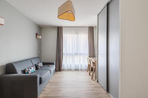 a living room with a couch and a table at Appart'City Confort Perpignan Centre Gare in Perpignan