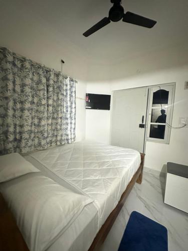 a white bed in a room with a ceiling fan at DM Elite Hospitality in Chikmagalūr