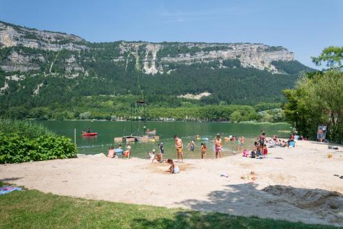 a group of people on a beach with a body of water at Logis Hotel L'Embarcadère in Nantua