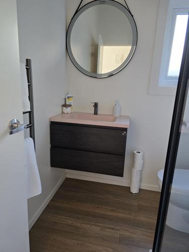 a bathroom with a sink and a mirror on the wall at Private Studio Sleepout in Aucklands Convenient Location in Auckland