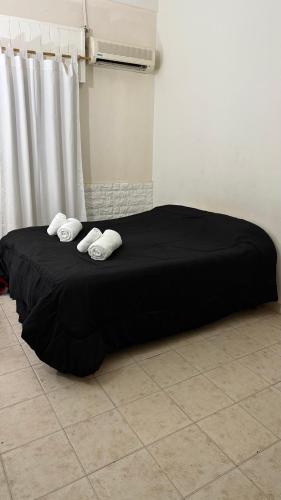 a black bed with white pillows on the floor at Departamento familiar cerca del aeropuerto in Ezeiza
