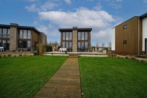 a large building with a grass field in front of it at Maas Villa Havenzicht | 10 personen in Kerkdriel