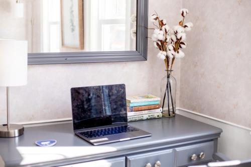 a laptop computer sitting on a desk with a vase of flowers at Blue Bear inn in Francestown