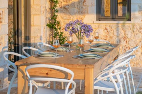 a wooden table with chairs and glasses of wine at NEW LUXURY STONE Villa AMENTE in Fiskardho
