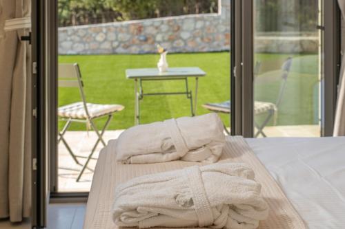 two towels sitting on a bed in front of a glass door at NEW LUXURY STONE Villa AMENTE in Fiskardho