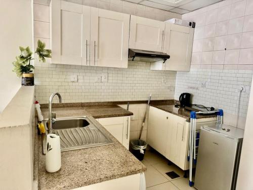 a kitchen with white cabinets and a sink at Not far from metro and WTC in Dubai