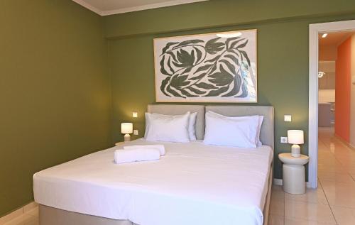 a bedroom with a white bed with a painting on the wall at Come Si Deve City Apartments, by Zantewize in Zakynthos Town