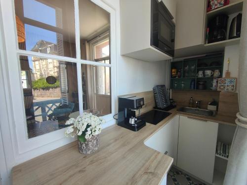 une cuisine avec une fenêtre et un vase de fleurs dans l'établissement Pépite à 100m de la plage, à Dinard