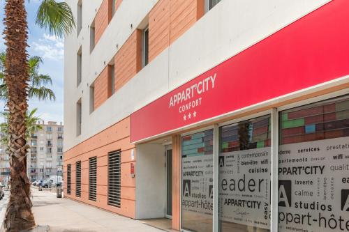 a building with a red sign on the side of it at Appart'City Confort Perpignan Centre Gare in Perpignan