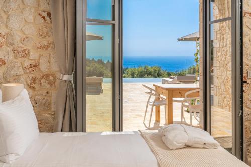 a bedroom with a bed and a table with a view at NEW LUXURY STONE Villa AMENTE in Fiskardho