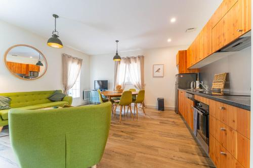 a kitchen and living room with a green couch and a table at Domaine du Flamand - Gîtes du Pin Sec côté OCEAN in Naujac-sur-Mer