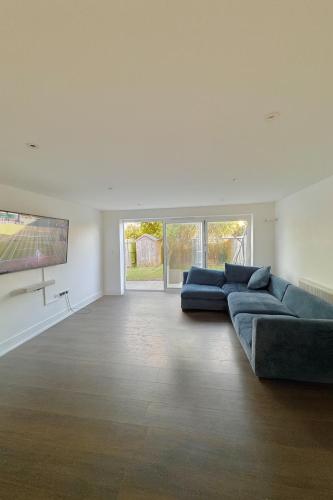 a living room with two blue couches and a tv at Coastal 3BR Garden & Parking in Eastbourne