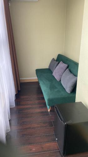 a living room with a green couch with two pillows at Arnas hotel in Almaty
