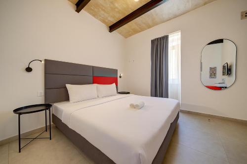 a bedroom with a large white bed and a mirror at Casa San Domenico 3 by Vallettastay in Valletta