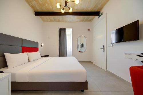 a bedroom with a large white bed and a tv at Casa San Domenico 3 by Vallettastay in Valletta