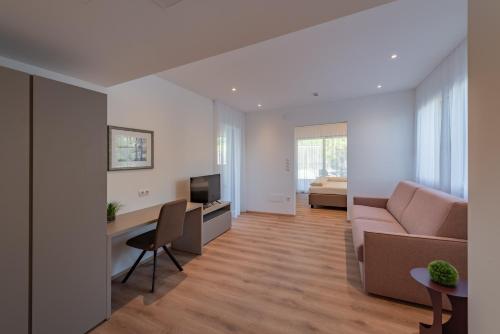 a living room with a couch and a television at Garni Hotel Sonnleitenhof in Caldaro