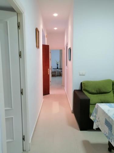 sala de estar con sofá verde y pasillo en Piso centro de Cádiz, en Cádiz
