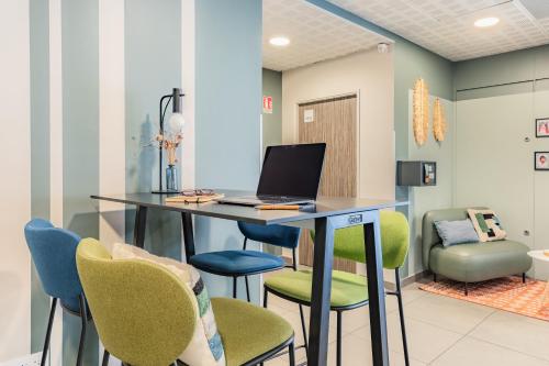 a room with a desk with a laptop and chairs at Appart'City Confort Perpignan Centre Gare in Perpignan