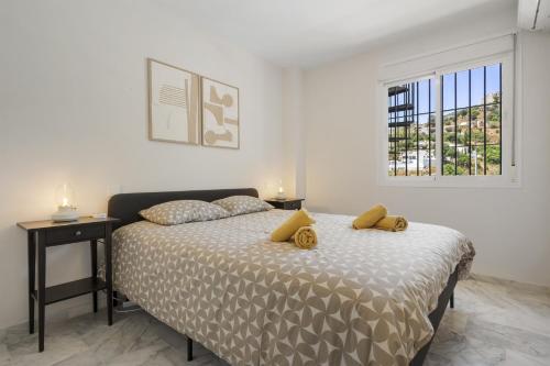 ein Schlafzimmer mit einem Bett mit gelben Kissen und einem Fenster in der Unterkunft Rooftop Torrequebrada Holiday Apartment in Torremuelle