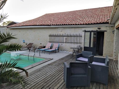 a wooden deck with chairs and a swimming pool at Gite Sud Deux Sevres in Marigny