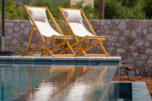 two chairs sitting next to a swimming pool at NEW LUXURY STONE Villa AMENTE in Fiskardho