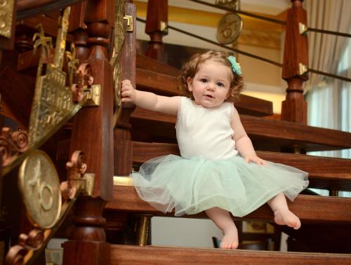a little girl in a dress sitting on a rail at Oğlakcıoğlu Park Otel in Izmir