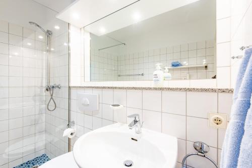 een witte badkamer met een wastafel en een spiegel bij Steger-Hüs Wohnung 37 in Rantum