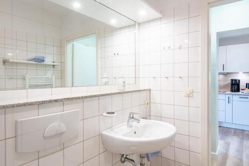 Un baño blanco con lavabo y espejo. en Steger-Hüs Wohnung 33, en Rantum