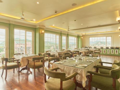 Un comedor con mesas y sillas y ventanas. en Moustache Select Udaipur, en Udaipur