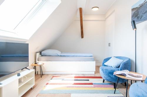 a small attic bedroom with a bed and a chair at Steger-Hüs Wohnung 41 in Rantum