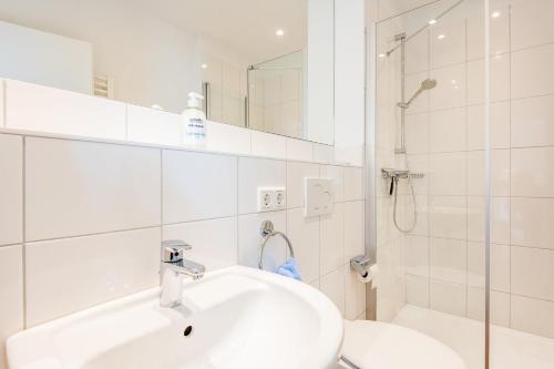 a white bathroom with a sink and a shower at Steger-Hüs Wohnung 42 in Rantum