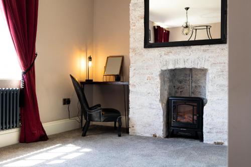 a room with a fireplace with a chair and a mirror at The Boat House Luxury Apartments Scarborough in Scarborough