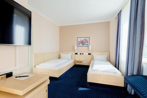 a hotel room with two beds and a tv at Rugs Hotel Augsburg City in Augsburg