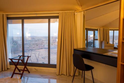 a living room with a desk and a large window at Stars Gate Camp in Al Wāşil