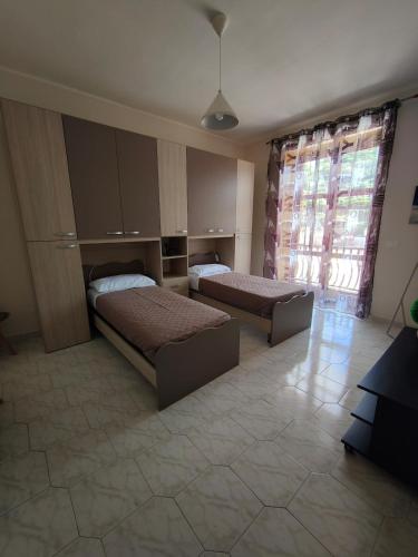 a bedroom with two beds and a large window at Hyria Intero Appartamento in centro città in Avellino