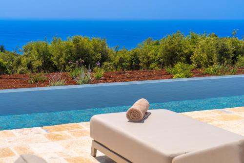 a white chair with a towel on it next to a pool at NEW LUXURY STONE Villa AMENTE in Fiskardho