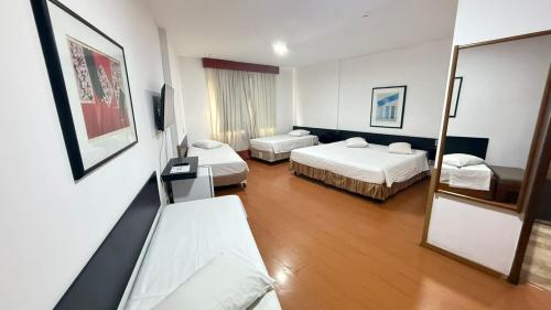 a hotel room with two beds and a mirror at César Park Hotel in Juiz de Fora