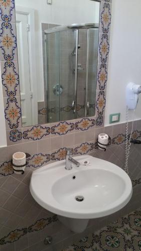 a bathroom with a white sink and a mirror at Hotel A Cannata in Santa Marina Salina