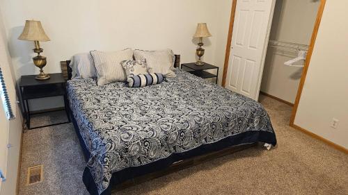 ein Schlafzimmer mit einem Bett mit zwei Nachttischen und zwei Lampen in der Unterkunft Hawthorne Hideaway in West Des Moines