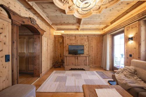 a living room with wooden walls and a television on a table at Familien- & Vitalhotel Auenhof in Fulpmes