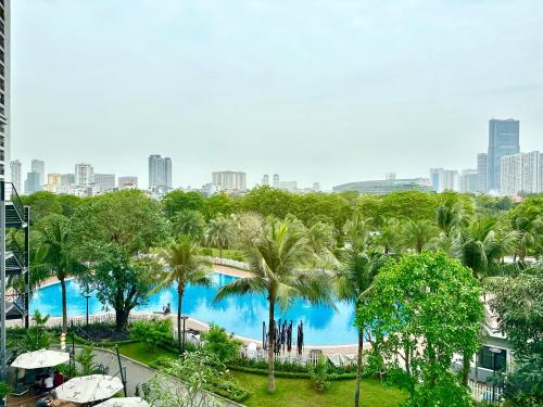 a view of a pool with palm trees and a city at Luxury Studio With Swimming Pool, Gym And Tennis Courts In City Center in Hanoi