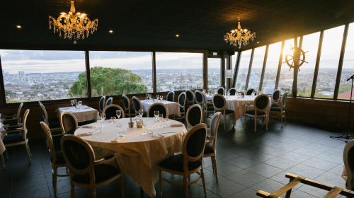 a dining room with tables and chairs and chandeliers at Le Moulin d'Orgemont, hébergements & restaurants Argenteuil in Argenteuil