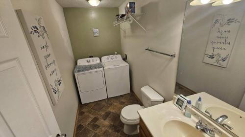 a bathroom with a toilet and a washer and dryer at Hawthorne Hideaway in West Des Moines
