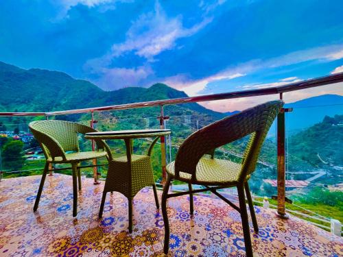 three chairs and a table on a balcony with a view at The Kempty Castle, Mussoorie in Mussoorie