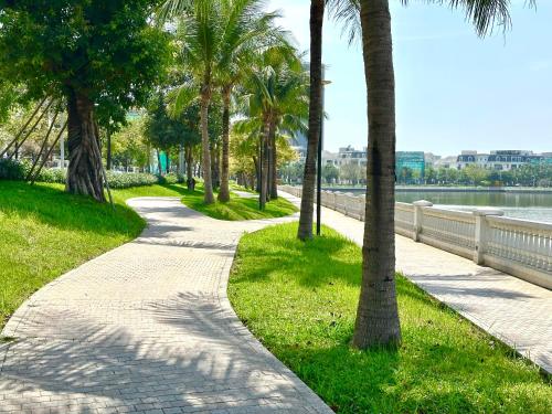 a path with palm trees and a body of water at Luxury Studio With Swimming Pool, Gym And Tennis Courts In City Center in Hanoi