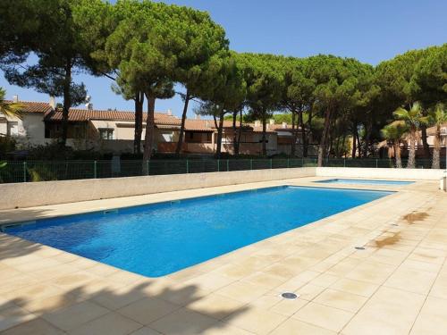 une piscine dans une cour avec des arbres en arrière-plan dans l'établissement Charmant T2 mezzanine climatisé avec piscine, proche plage et loisirs, pour 5 pers. - FR-1-607-77, au Cap d'Agde